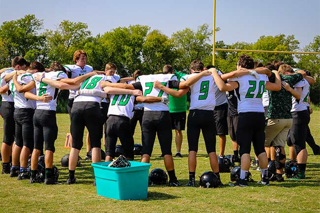 Denton Calvary's Varsity Football team circle up to pray before a game.